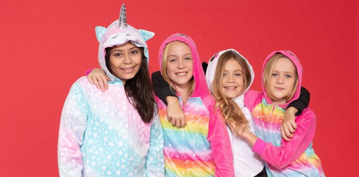Girls wearing unicorn onesies on red background