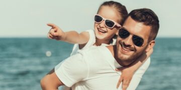 Father and daughter wearing sunglasses at the beach