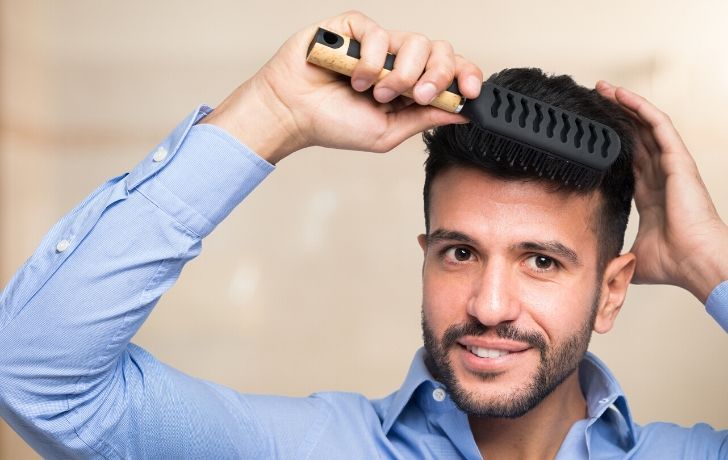 A man brushing his hair and smiling