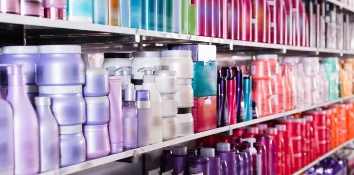 Many bottles of shampoo on shelves at a store