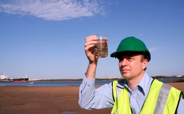 A person examining a sample on a beach